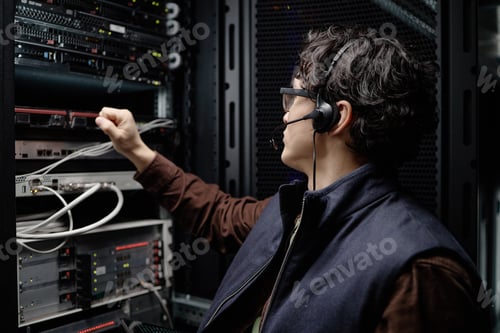 Preview: Young Adult Man Working in Server Room Wearing Headset and Vest