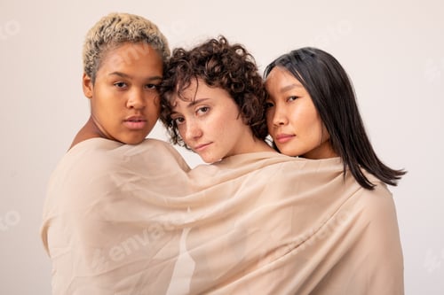 Preview: Group of young intercultural females wrapped into white linen looking at you