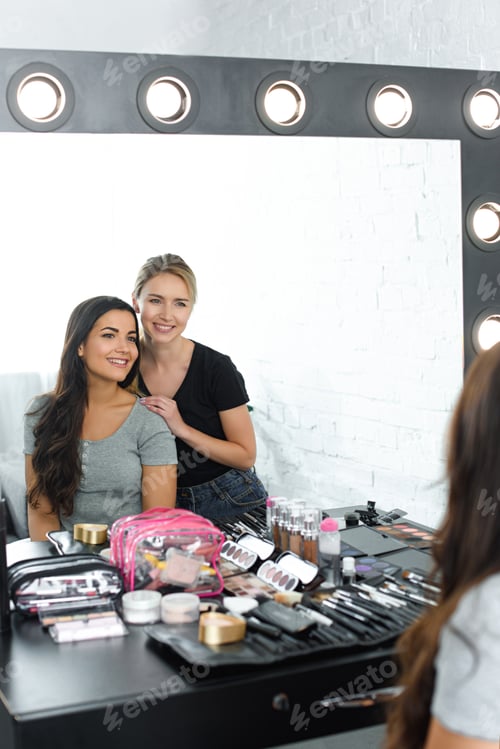 Preview: mirror reflection of beautiful young woman and smiling makeup artist