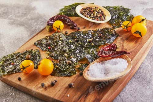 Preview: Crispy nori seaweed with cherry tomatoes and spices on a wooden board on gray concrete.
