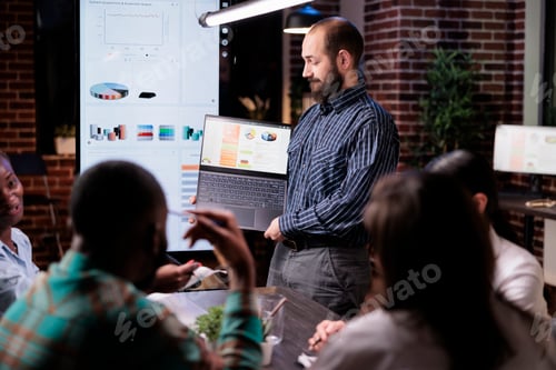 Preview: Caucasian man standing in business office presenting turnover charts on laptop screen
