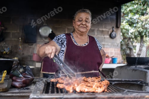 Preview: Latin poor woman cooking meat on a grill