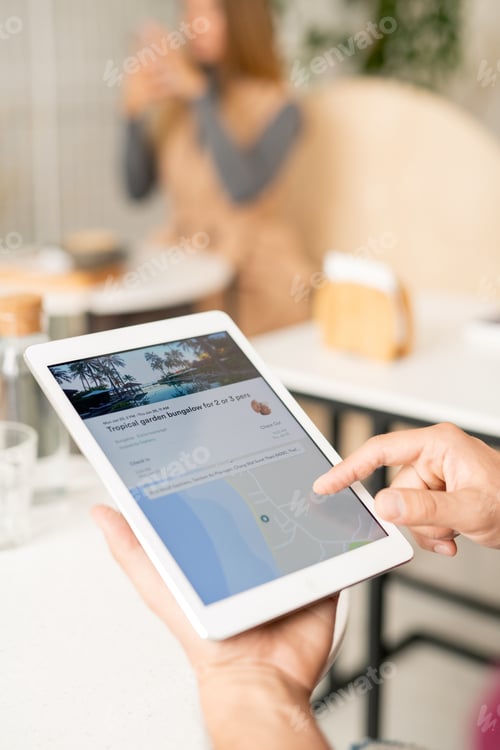 Preview: Human hand pointing at tablet screen while searching on website for travelers