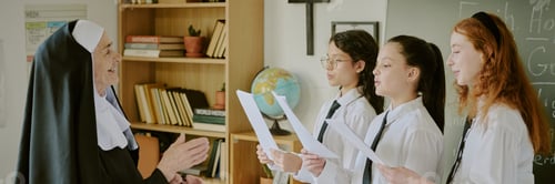 Preview: Group of Students Presenting to Smiling Senior Nun in Classroom