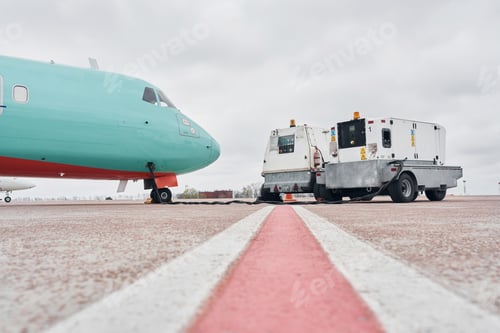 Preview: Vehicle nearby. Turboprop aircraft parked on the runway at daytime