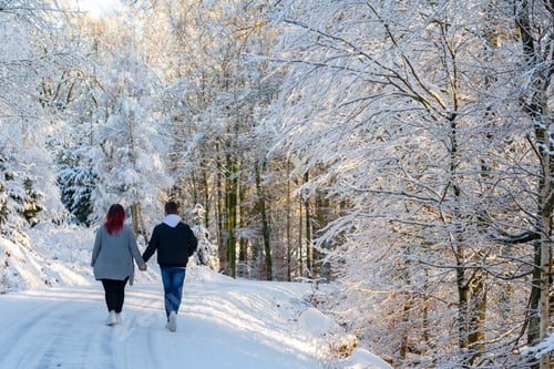 Preview: Winter romance. Young happy loving millennial couple in snowy winter forest landscape.