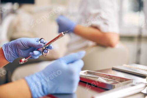 Preview: Focus on man hands holding instrument for manipulation with teeth