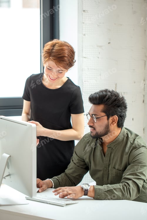 Preview: creative designers manager showing new startup idea on monitor for his female boss