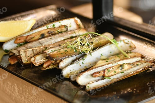 Preview: The shells knives, parsley and half a lemon on black plate