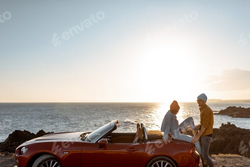 Preview: Lovely couple on the beach near the car on a sunset