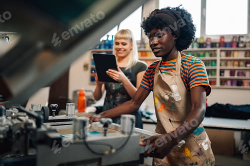 Preview: Interracial print shop worker putting screen printing plate on machine