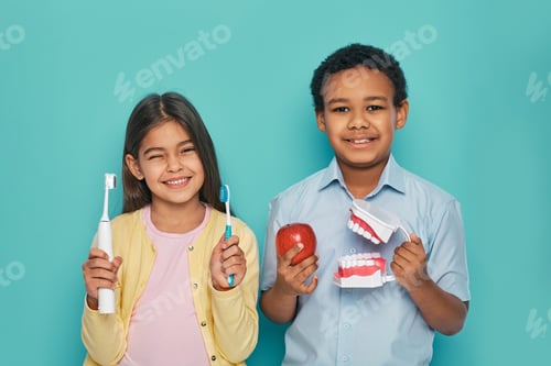 Preview: Multi-ethnic kids holding manual and electric ultrasonic toothbrushes. Oral hygiene concept to