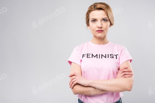 Preview: confident woman in pink feminist t-shirt with crossed arms, isolated on grey
