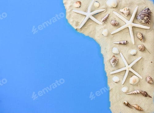 Preview: Overhead view of a travel flat lay with a blue background sand seashells and starfish