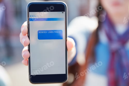 Preview: Closeup shot of a university student holding up a cellphone with a rude text message