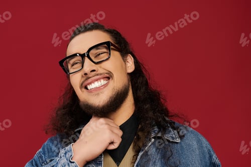 Preview: Handsome young bearded man smiling with confidence against a vibrant red background