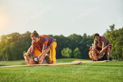 Preview: Adults Engaging in Partner Yoga on Grassy Lawn