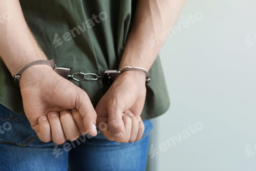 Preview: Man detained in handcuffs indoors, space for text. Criminal law