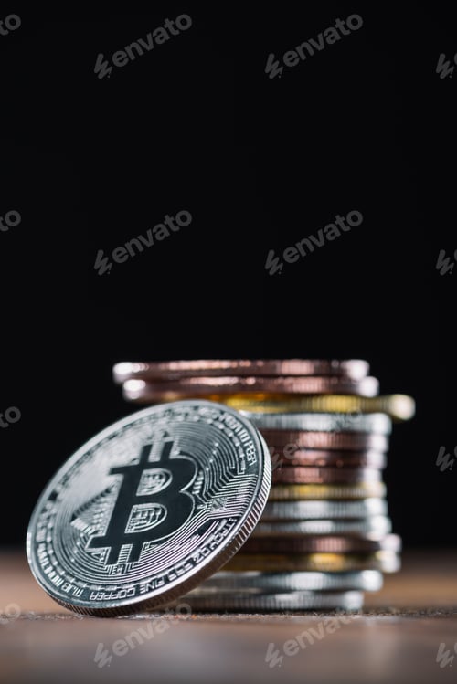 Preview: close up view of bitcoin leaning on stack of various bitcoins on black background