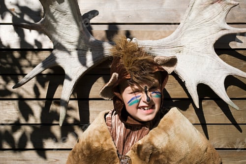 Preview: Boy dressed up as bear in front of moose antlers