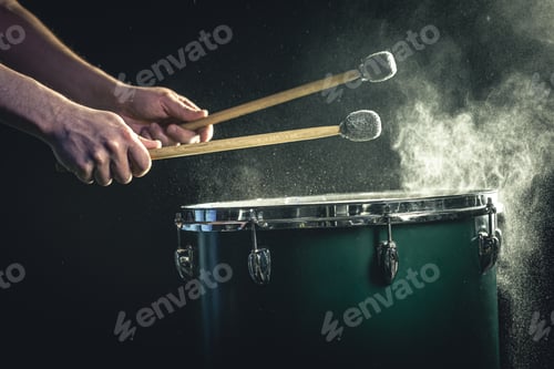 Preview: A man plays a musical percussion instrument with sticks on a dark background.