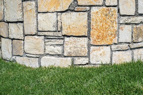 Preview: Part Of A Stone Structure Or Brick Wall From A Natural Stone On A Lawn For Abstractions And A Blank