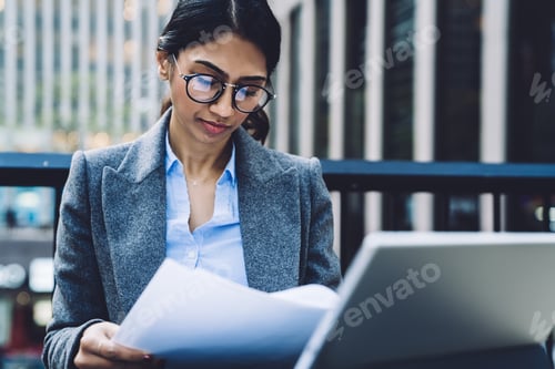 Preview: Intelligent business lady checking documents while using tablet on terrace