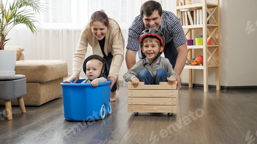 Preview: Happy family playing at home and having race in carts with children