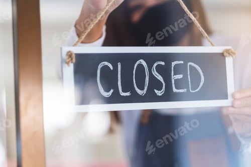 Preview: A waitress wearing protective face mask hanging closed sign on front door