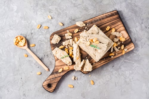 Preview: Pieces of sunflower and peanut halva and mint leaves on a cutting board on the table.