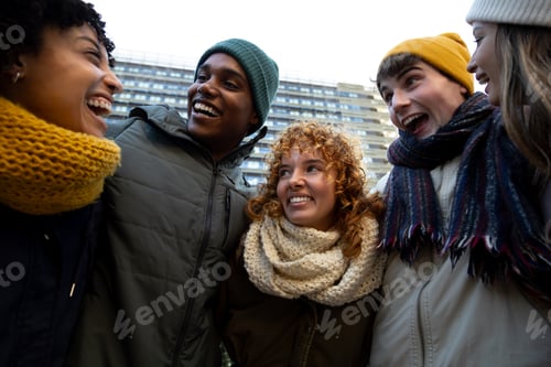 Preview: Multiracial college friends laughing and having fun embracing together during winter in the city.