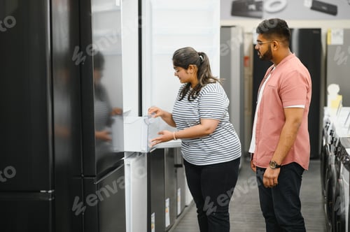 Preview: Indian family couple buying domestic refrigerator in supermarket.