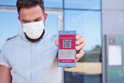 Preview: Man holding smartphone displaying on app mobile expired digital vaccination certificate for Covid-19