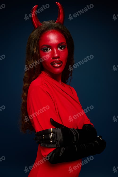Preview: A stunning woman in a devil themed Halloween costume poses dramatically against a dark backdrop