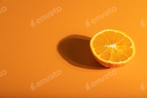 Preview: Ripe cut orange on orange pastel background. Side view, copy space, hard light.