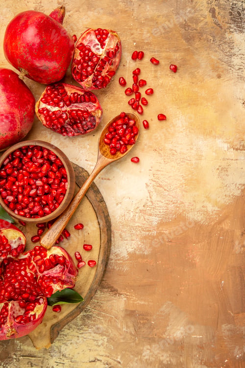 Preview: Top view whole (pomegranates) with their slices and a bowl seeds were put on the stump next to each
