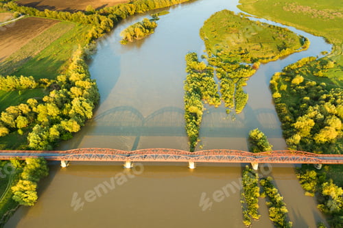 Preview: Aerial view of a narrow road bridge stretching over muddy wide river in green rural area