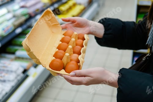 Preview: Woman chooses chicken eggs in a grocery store. Close up.
