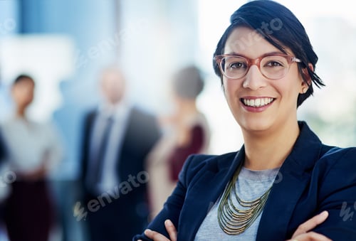 Preview: Cropped shot of a businesswoman standing with her arms crossed and her colleagues in the background