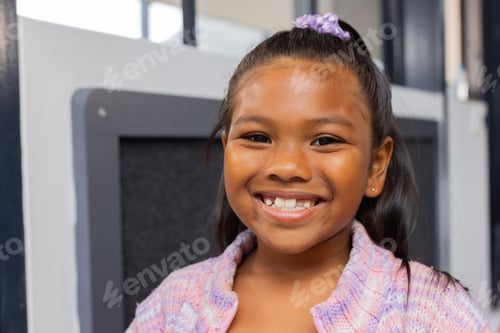 Preview: Biracial girl with a bright smile, wearing a purple hair accessory and a knit sweater
