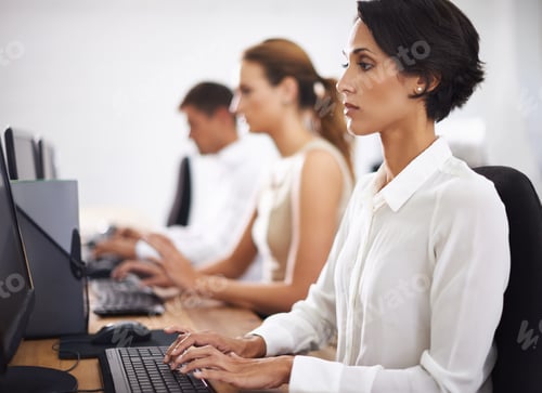 Preview: Shot of an attractive young office worker at her computer with her colleagues in the background