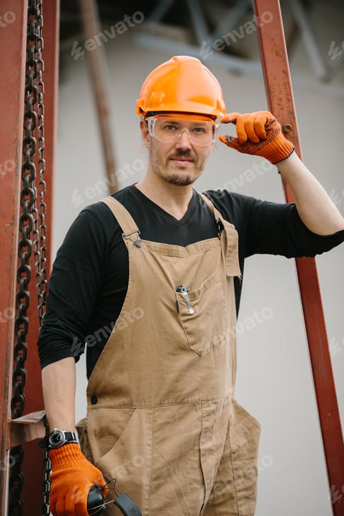 Preview: A construction worker in a protective helmet and glasses at the construction site of a grain silo.