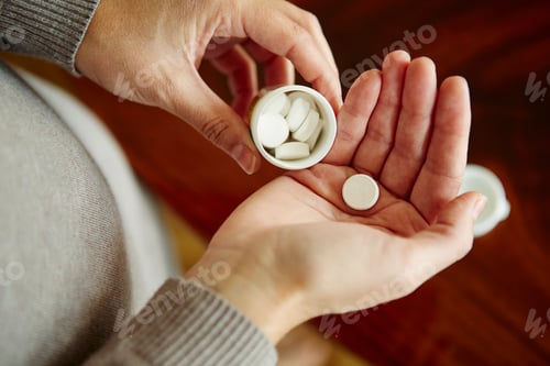 Preview: Young woman taking medication from tub, close-up