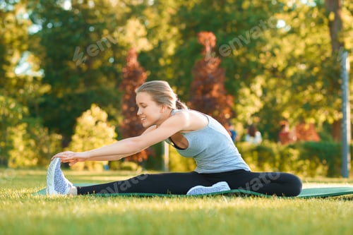Preview: Girl doing stretching on the park's grass