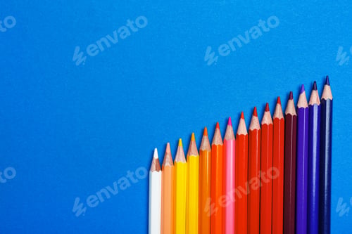 Preview: Color pencils on blue background, flat lay. Space for text
