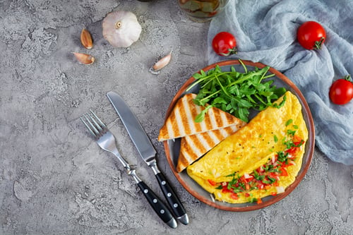 Preview: Fried omelette with tomatoes, onion and herbs. Delicious breakfast with eggs and toasts. Top view