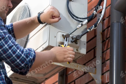 Preview: Closeup of male technician repairing outdoor air conditioner unit