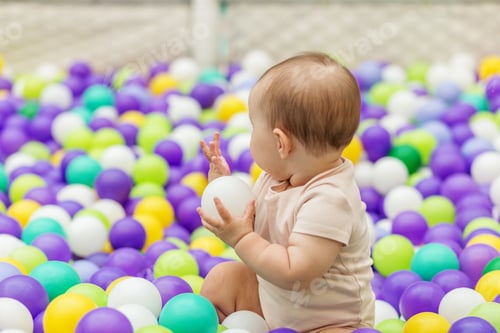 Vista previa: Baby exploring white ball in colorful ball pit. Early years