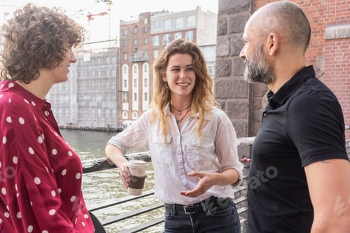 Preview: Man and female friends talking, river and buildings in background, Berlin, Germany