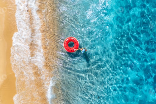 Preview: Aerial view of a young woman swimming with red swim ring